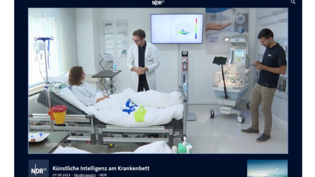 Eine Abbildung, die einen Entwickler, einen Arzt und einen Patienten im Krankenhaus zeigt, während sie gemeinsam das Konzept von 'Human-in-the-Loop' anwenden. Der Entwickler, der Arzt und der Patient sind auf dem Bild zu sehen, wie sie zusammenarbeiten und Informationen austauschen.